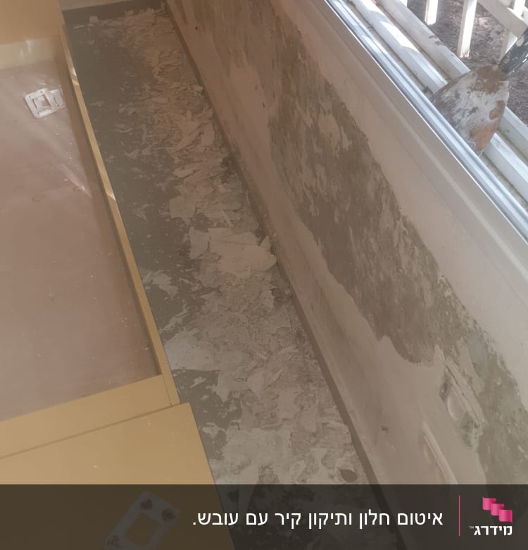 קיר מתקלף ליד חלון עם סימני רטיבות